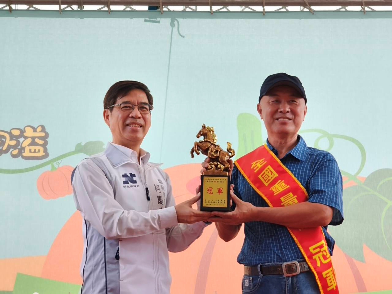 來自淡水區的農友林建訓(右)以重達773台斤的巨無霸南瓜勇奪重量組冠軍,也是第九度取得重量組冠軍頭銜,副秘書長柯慶忠(左)頒發獎座表揚